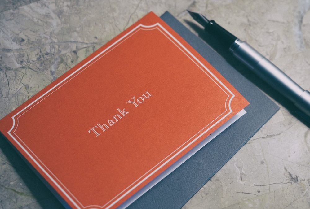 Thank you card laying next to a pen